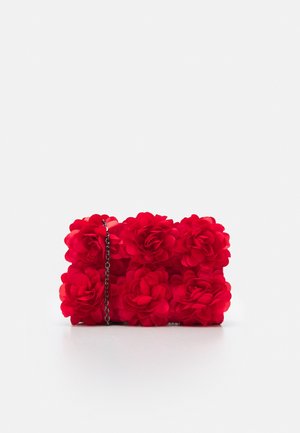 Petit sac à main rectangulaire rouge recouvert de grandes fleurs en tissu avec une fine chaîne métallique sur fond blanc.