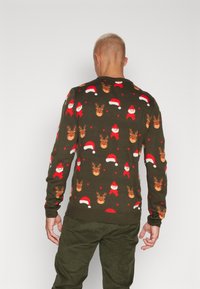 Mönstrad stickad tröja i mörkgrön med ett festligt mönster som visar tomtar, renar och röda jultomtedräktsmössor. Ribbad ärmar och nederkant.