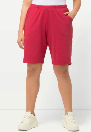 Rode katoenen shorts met een elastische tailleband en zijzakken, met een relaxte pasvorm. Gepaard met witte sneakers voor een casual look.