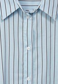 Ljusblårandig skjorta med vertikala svarta ränder, spetsig krage och vita knappar längs framtill. Slät tygstruktur.