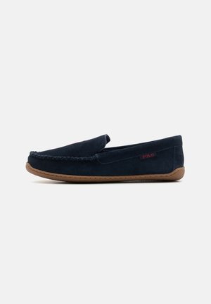 Marineblauwe suède instappers met gestikt detail, een bruin rubberen zool en een rode 'POLO'-logo aan de zijkant. Klassiek moccasin-ontwerp.