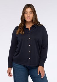 Camisa navy de botones en una tela suave, con cuello, mangas largas y botones de oro rosa en el frente para un contraste.