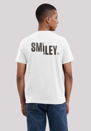 White cotton t-shirt featuring bold black "SMI|LEY" text on the back. Standard fit with short sleeves and a round neckline.