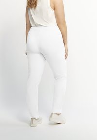 Witte skinny jeans met een gladde textuur, hoge taille en minimalistisch ontwerp, gecombineerd met off-white casual schoenen.