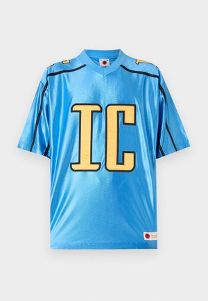 Jasnomodrý športový dres s krátkym rukávom s veľkými žltými písmenami "IC" a čiernymi lemovaniami na pleciach a bokoch.