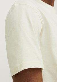 Lys beige bomulds t-shirt med en blød tekstur og korte ærmer. Har en rund halsudskæring og en pæn syning på kanterne.
