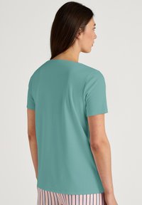 Korte mouwen top in teal, gemaakt van zachte stof. Eenvoudig ontwerp met een ronde halslijn en een relaxed fitting. Gladde textuur, geen zichtbare patronen.