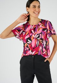 Blusa de manga corta con cuello redondo que presenta un vibrante patrón floral en rosa, naranja y púrpura sobre un fondo negro.