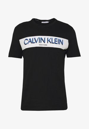 Czarny bawełniany t-shirt z białym poziomym panelem zawierającym napis "CALVIN KLEIN NEW YORK" w niebieskich literach, okrągły dekolt i krótkie rękawy.