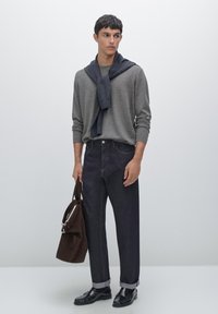 Maglietta grigia a maniche lunghe, jeans in denim scuro con risvolti, scarpe in pelle nere, borsa in suede marrone, sovrapposizione casual con sciarpa.