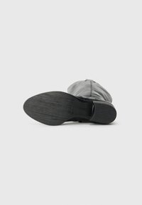 Schwarze Leder-Stiefelette mit einer strukturierten Gummisohle, runder Zehenform und seitlicher Schnalle. Glattes Obermaterial mit minimalen Designelementen.