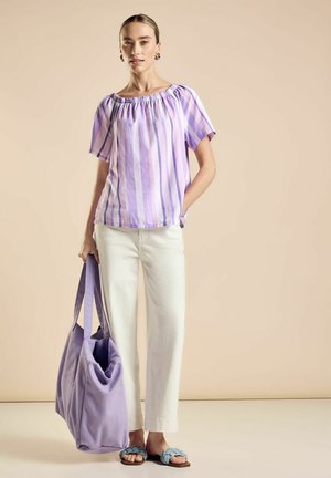 Lila gestreifte Bluse mit gerafftem Halsausschnitt, weiße Leinenhose, helllila Umhängetasche und blaue geflochtene Slipper.