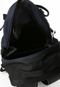 Marineblauer Rucksack mit einem Reißverschluss, aus strapazierfähigem Stoff gefertigt, beinhaltet ein Innenfach und verfügt über eine schwarze, strukturierte Unterseite und Riemen.