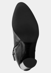 Bottine en cuir noir avec un bout rond, fermeture éclair sur le côté, texture lisse et un talon court et cylindrique. Semelle en caoutchouc.