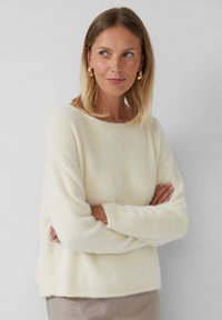 Crème-kleurige textuurtrui met lange mouwen, een ronde halslijn en een ontspannen pasvorm. Zacht, pluizig materiaal met een subtiele glans.