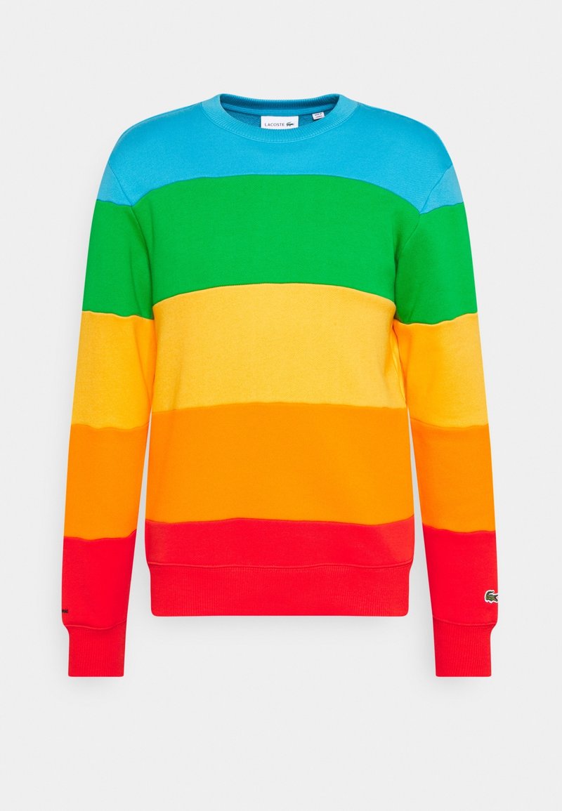 Sweatshirt à col rond avec des rayures horizontales en bleu, vert, jaune, orange et rouge, arborant un petit logo Lacoste sur le poignet de la manche gauche.