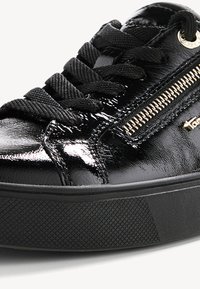 Fekete patentbőr sneaker lekerekített orral, lapos fekete fűzőkkel, oldalsó cipzár részlettel és textúrált gumitalppal. Arany hardver díszítések.