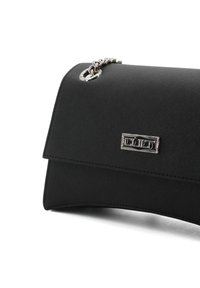 Borsa a mano nera con texture liscia, chiusura a patta, hardware in tonalità argento e dettagli decorativi in catena. Design compatto e strutturato.