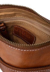Brun läderpung med dragkedjestängning, med en beige foder, flera fack och en sydd logotags inuti.