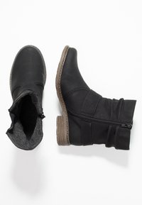 Botas negras de tobillo con un exterior de cuero texturizado, un suave forro de tela gris y una cremallera lateral. Presentan un tacón de madera bajo y un diseño arrugado.
