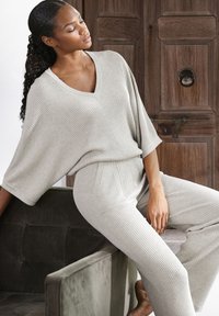 Lichtbeige gebreide loungewearset met een V-hals, wijde mouwen, ribbelstructuur en elastische broek met zijzakken.