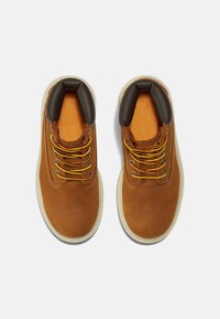 Scarpe in pelle marrone con lacci gialli e rossi, colletto imbottito marrone scuro e suola chiara. Sottopiede arancione testurizzato visibile.