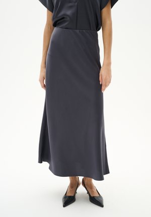 Long, dark gray skirt made of smooth fabric, with a flowing silhouette and side slit; paired with pointed black heels.