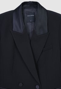 Blazer nero con rever in raso, spalle strutturate, due bottoni frontali e taschino sul petto. Etichettato "CALLIOPE," taglia S. Tessuto liscio.