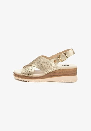 Sandalias de cuña metálicas doradas con diseño floral recortado, correa de tobillo ajustable, plantilla acolchada y suela exterior de goma texturizada.