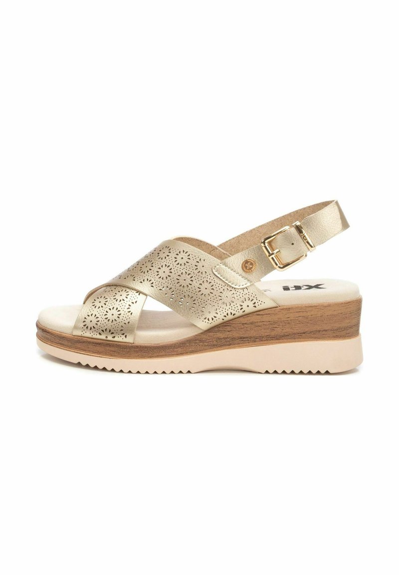 Sandalias de cuña metálicas doradas con diseño floral recortado, correa de tobillo ajustable, plantilla acolchada y suela exterior de goma texturizada.