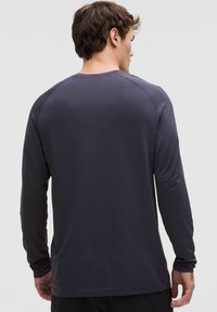 Koszula z długim rękawem w ciemnoszarej tkaninie o teksturowanym wzorze, z okrągłym dekoltem i rękawami raglanowymi, idealna do aktywnego noszenia.