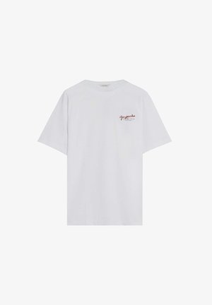 Camiseta blanca de manga corta con pequeño texto rojo en cursiva "Gazpacho" en la parte superior izquierda del pecho.