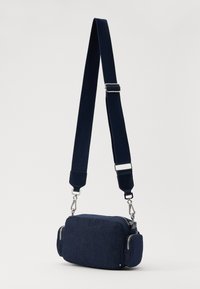 Granatowa torebka na ramię wykonana z teksturowanej tkaniny. Posiada prostokątny kształt, dwie kieszenie na zamek oraz regulowany pasek z metalowymi akcesoriami.