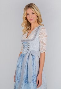 Traditionelles blaues Kleid mit Spitzenärmeln, einer taillierten Taille und dekorativen Knöpfen, mit einem Satinegürtel und floralen Mustern im Rock.