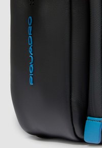 Schwarze Lederhandtasche mit strukturiertem Finish, akzentuiert durch ein leuchtend blaues Logo und blauen Riemen auf der Seite.