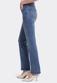 Blauwe denim jeans met een rechte pasvorm, vijf zakken en zichtbare stiksels. Gecombineerd met beige hoge hakken.