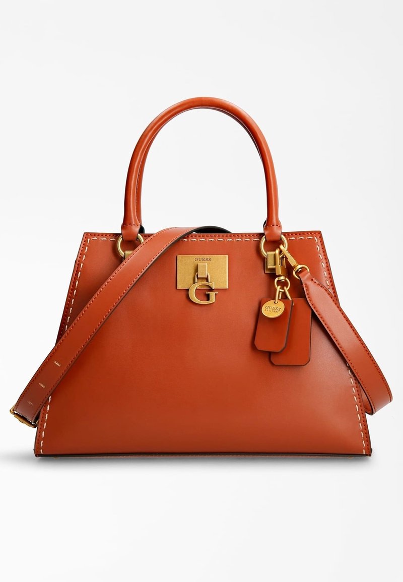 Sac à main en cuir marron avec bords cousus, plaque logo "Guess" dorée, double poignées, bandoulière amovible et deux étiquettes suspendues.