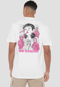 White t-shirt featuring a graphic design of a girl with black hair, pink accents, and figures in hooded outfits. Text in pink below.