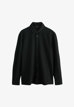 Čierna rebrovaná košeľa na gombíky s golierom, dlhými rukávmi a piatimi gombíkovými zapínaniami. Textúrovaná tkanina pridáva hĺbku dizajnu.