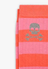 Calcetines a rayas en un brillante color naranja y rosa, con un diseño de calavera y tibias en gris. Textura de punto con puños acanalados.