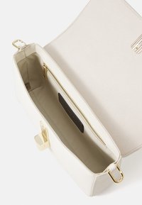 Witte leren handtas met een gladde textuur, voorzien van een gouden rits en hardware. Het interieur heeft een beige voering en een branded zwart label.