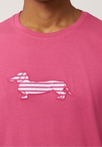 Rosa Baumwoll-T-Shirt mit gestickter Umrandung eines Dackels mit gestreiftem Muster in helleren Rosa-Tönen. Kurze Ärmel und runder Ausschnitt.