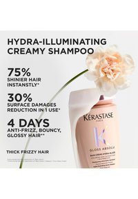 Fles Kérastase Gloss Absolu shampoo met een crèmekleurige bloem, die glanzender, minder beschadigd en pluisvrij haar voor dik, kroeshaar binnen 4 dagen promoot.