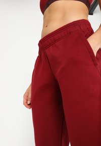 Pantalones de chándal burdeos con un corte ajustado, cintura elástica y bolsillos laterales, fabricados con una suave tela texturizada.