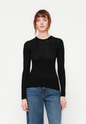 Svart langermet genser med en tettsittende silhuett. Laget av teksturert stoff, har den rund hals og ribbestrikkede detaljer, kombinert med blå jeans.