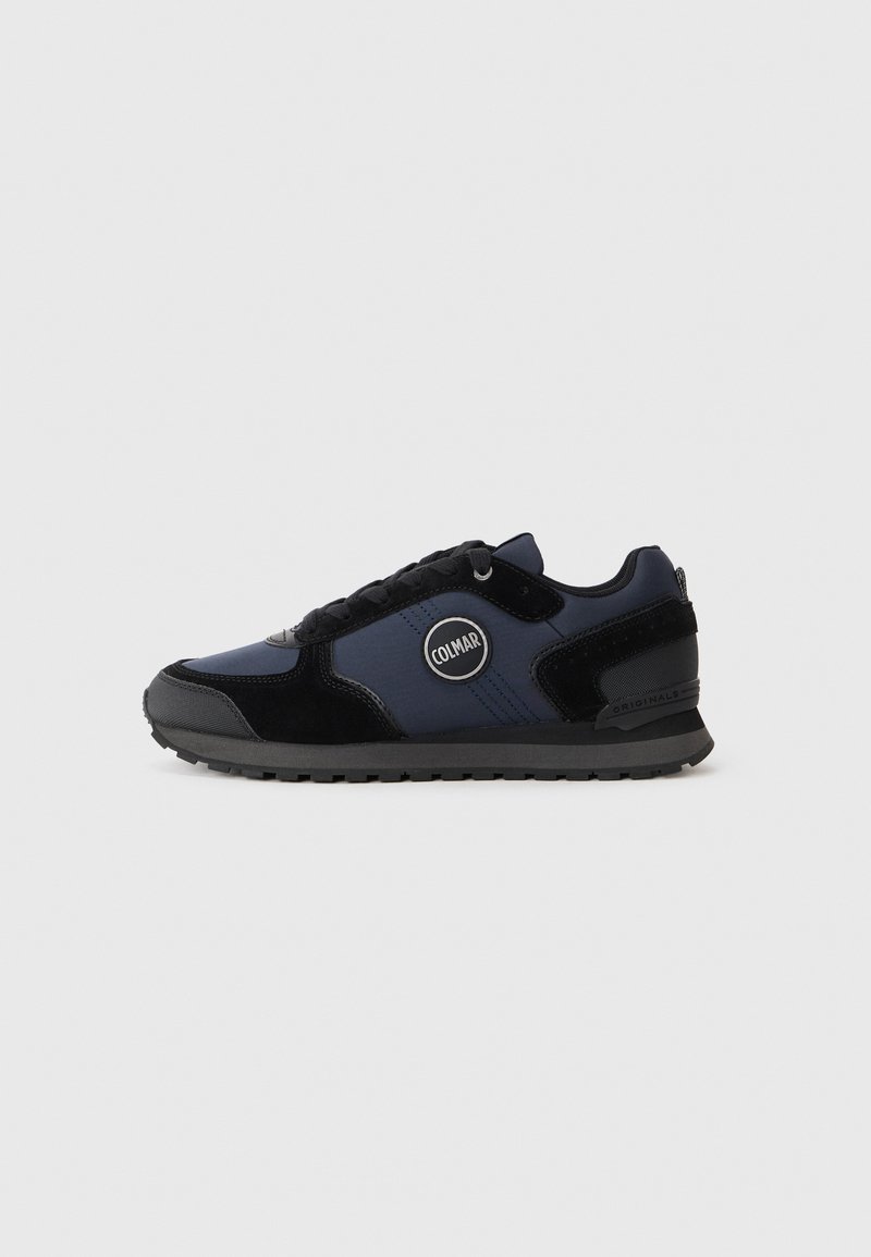Black and navy athletic sneaker featuring a mesh upper, suede accents, round logo patch on the side, textured sole, and lace-up design.