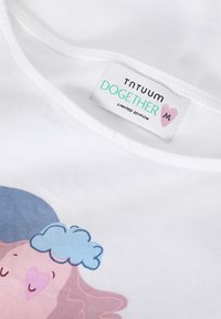 Balta medvilninė marškinėliai su pasteliniu piešiniu, kuriame pavaizduotas personažas su rožiniais plaukais ir mėlyna debesimi, pažymėti "TNTUUM DOGETHER LIMITED EDITION."