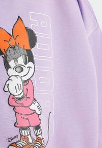 Felpa viola con un grafico di un personaggio con un grande fiocco arancione. Il testo recita "ADIDAS" accanto al personaggio. Tessuto morbido.