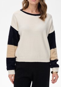 Roomkleurige trui met marineblauwe en beige kleurvlakken, met zachte mouwen. Heeft een losse pasvorm, brede boothals en geribbelde boorden aan de manchetten en zoom.