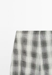 Tessuto grigio e bianco a fantasia, caratterizzato da un design a quadri tessurizzato con strisce alternate. Materiale leggero con una finitura morbida.